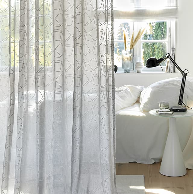 Transparente Gardine mit Muster im Schlafzimmer.
