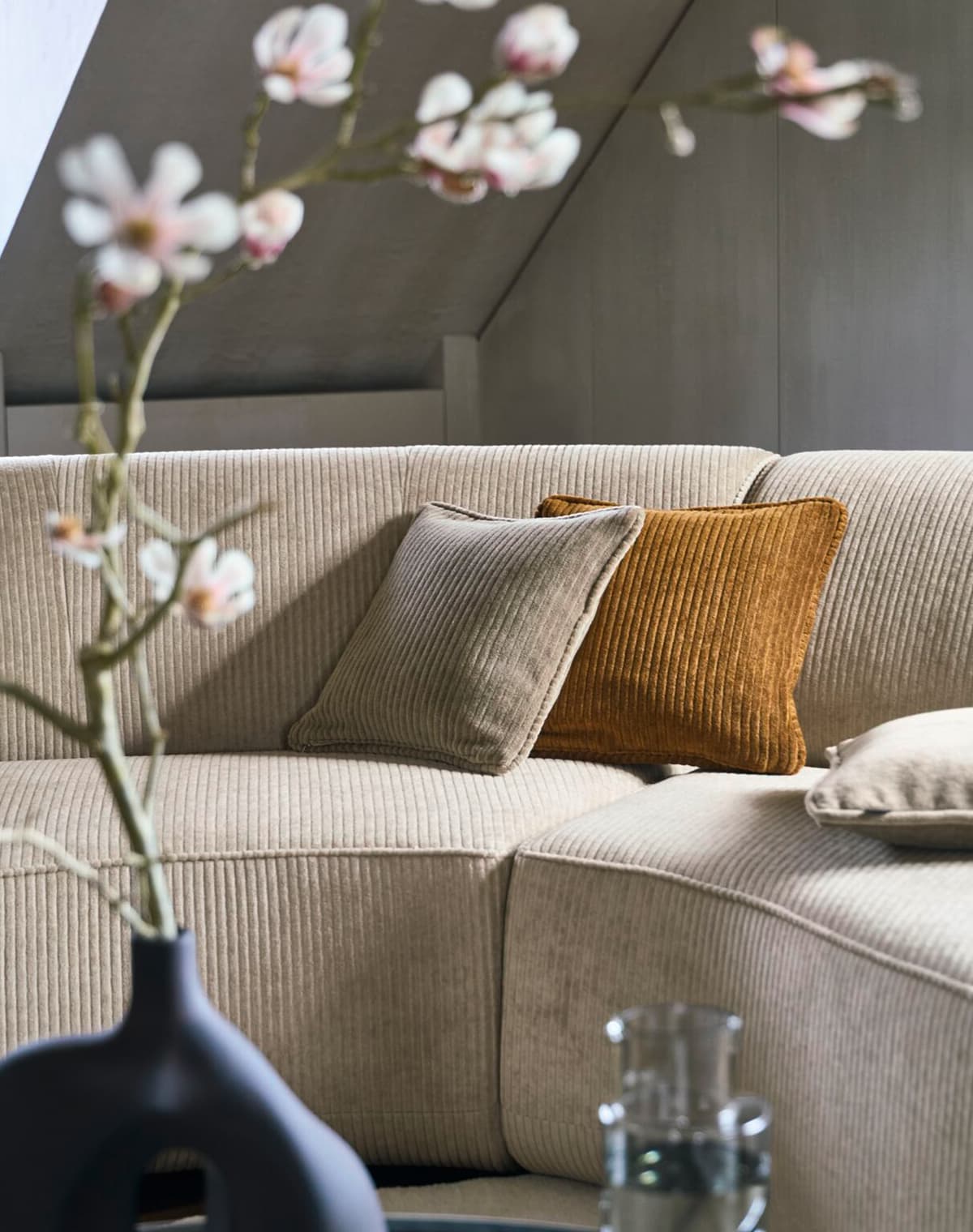 Eine Aufnahme von einem beigen Sofa mit zwei Kissen darauf, beides in Erdtönen.