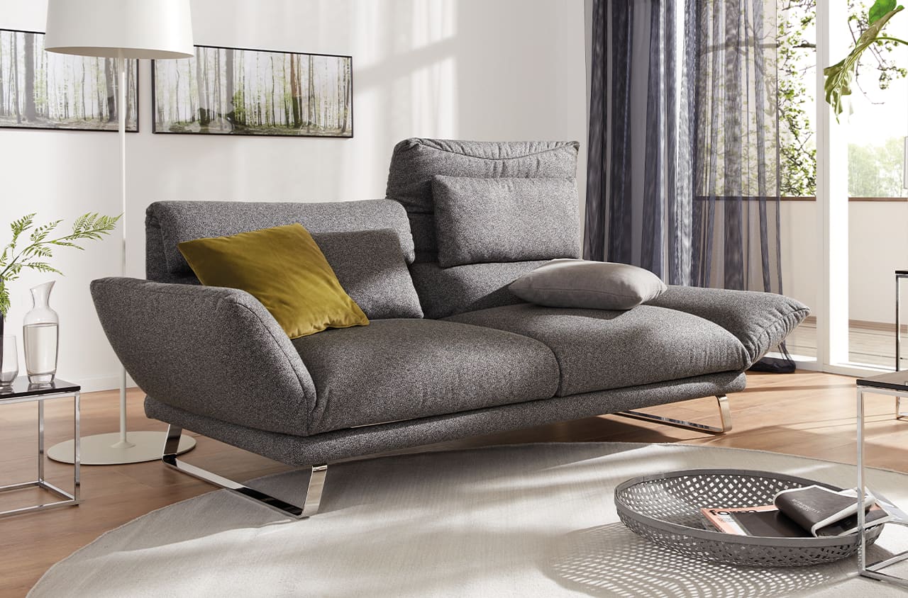 Weißes Sofa mit schwarzen, braunen und weißen Deko-Kissen in einem grauen Raum mit weißen Akzenten