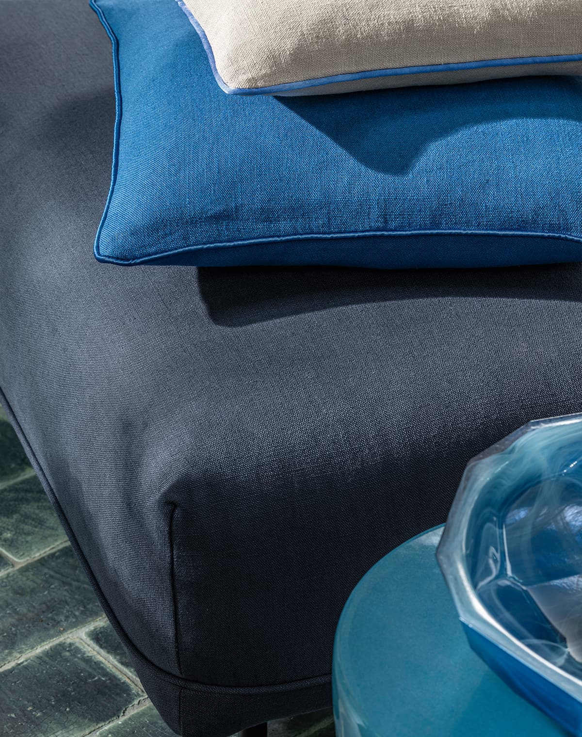 Ein blaues und ein weißes Kissen auf einem dunkelblauem Sofa.