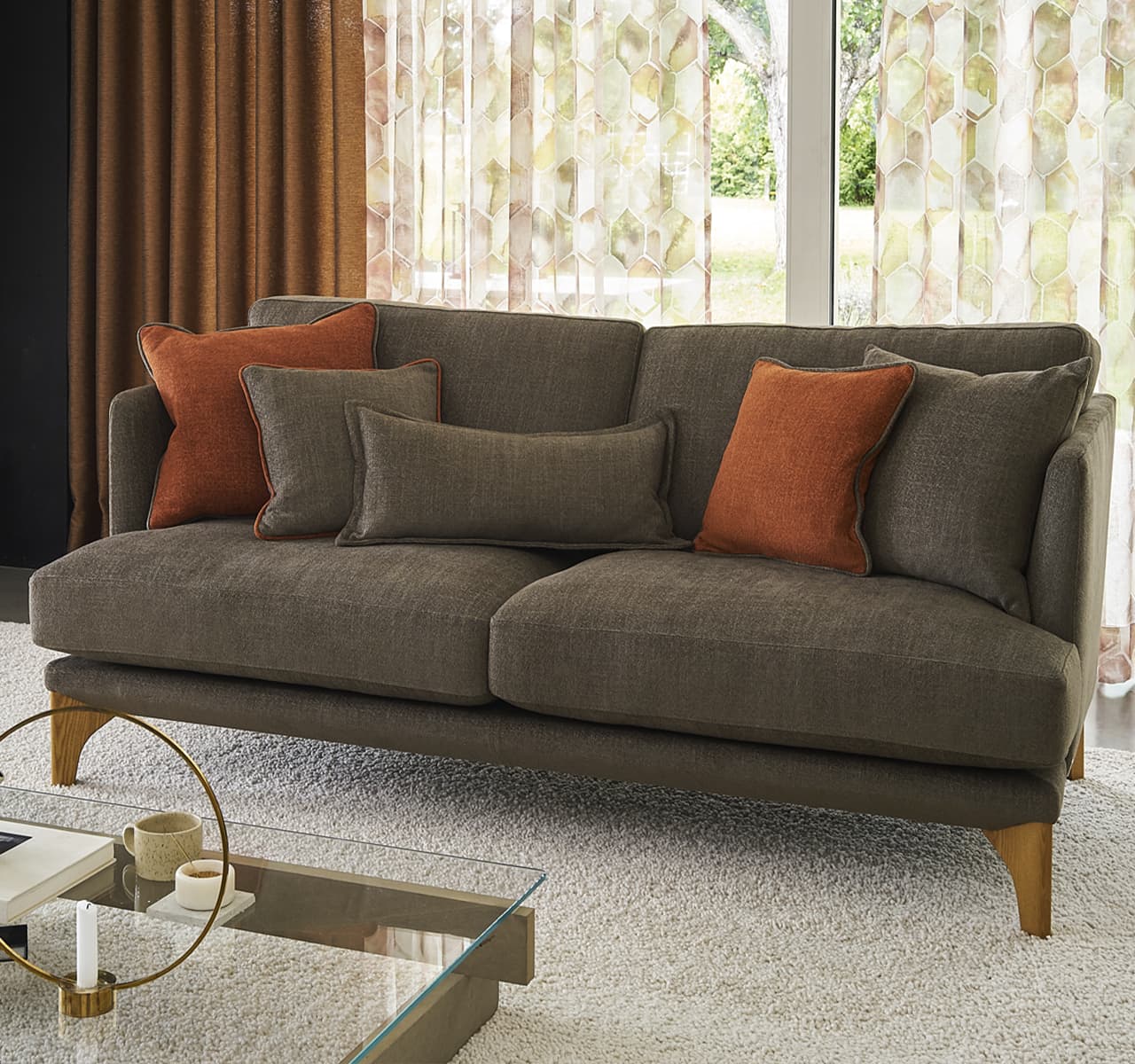 Braunes SOfa mit orangenen Kissen in einem hellen warmen Raum