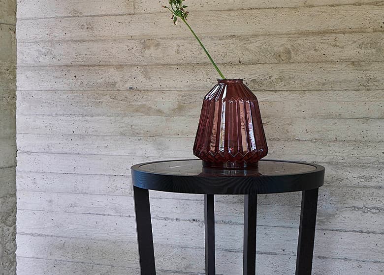 Nahaufnahme von dem Mood Beistelltisch in schwarz vor einer Wand mit einer Vase drauf