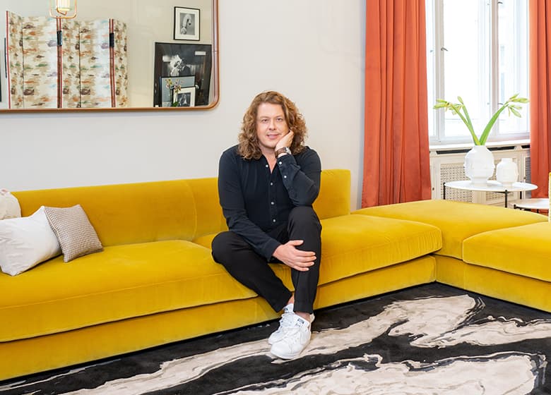 Portrait von Designer Frank Stüve auf einem gelben Sofa