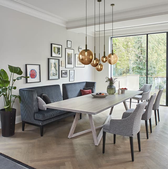 Graue Stühle und eine blaue Bank um einen weißen Tisch herum in einem gemütlichen Esszimmer