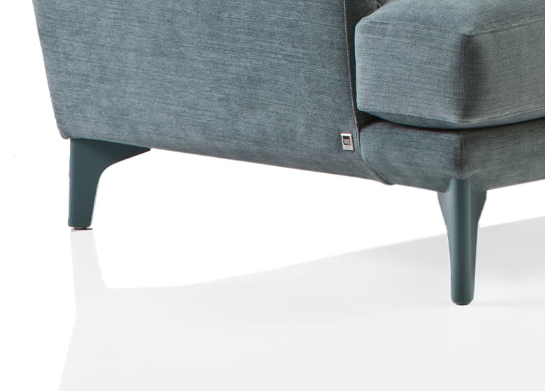 Nahaufnahme eines Holzfußes eines grünen Sofas.