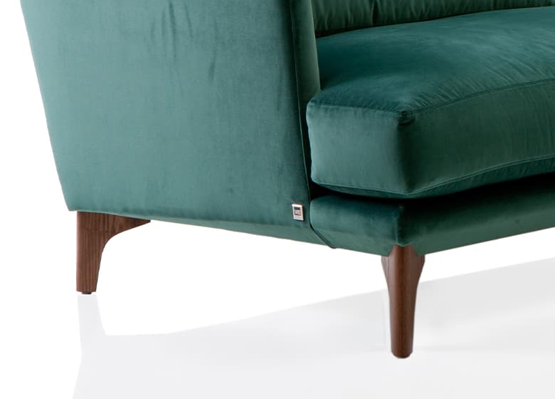 Nahaufnahme der Holzfüße eines grünen Sofas.