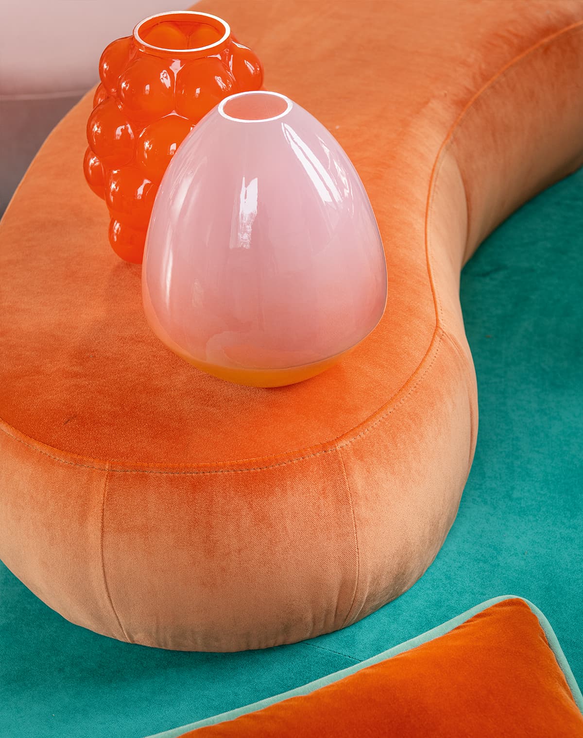 Ein orangener Pouf mit Vasen in orange und rosa.