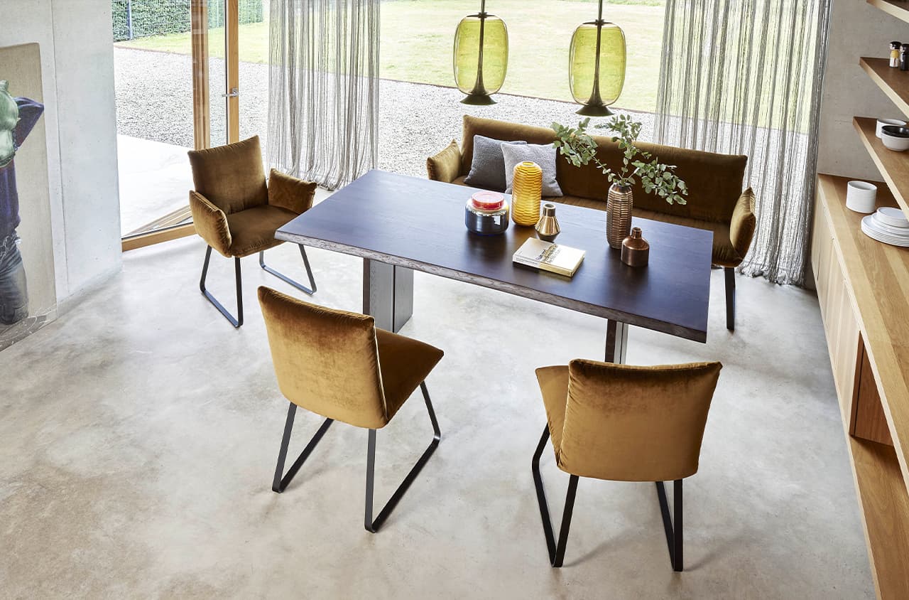 Drei braune Stühle und eine Bank um einen schwarzen Tisch