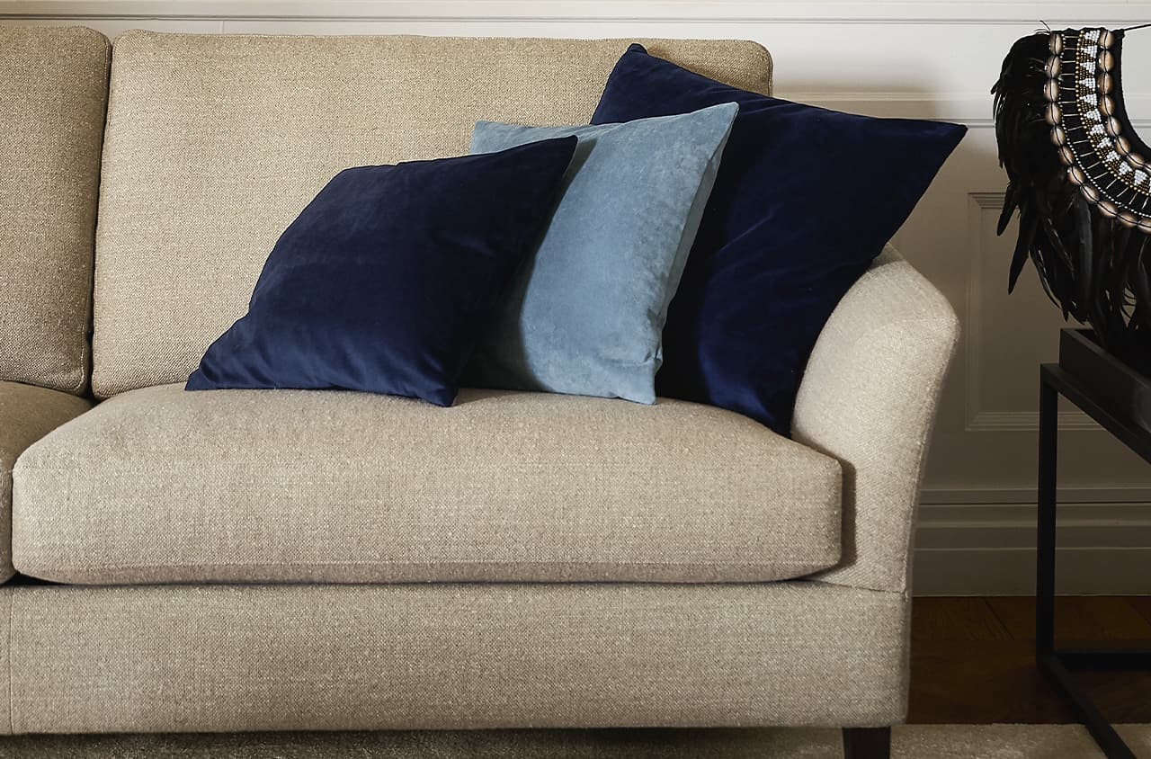 Angeschnittene Ansicht eines beigen Sofas mt blauen Deko-Kissen