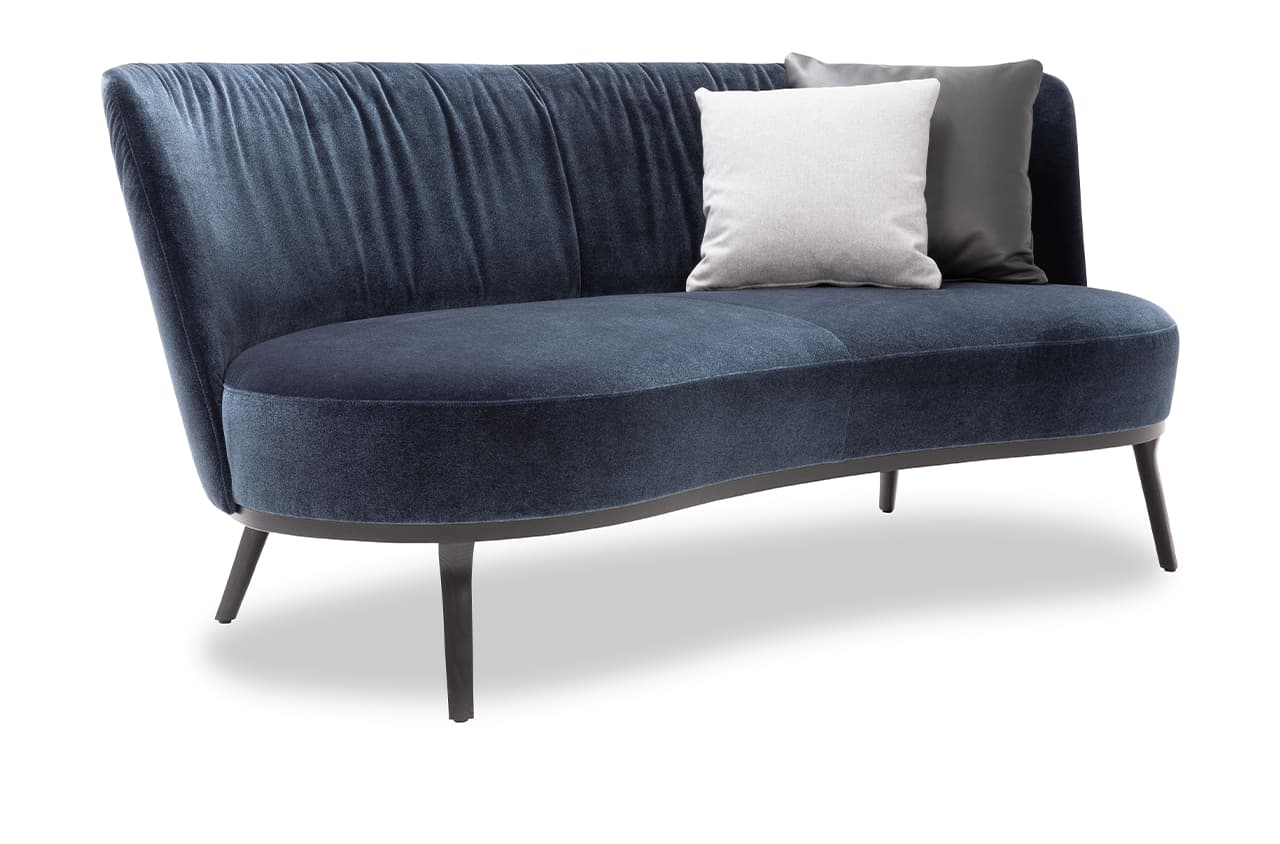 Freisteller eines blauen Samt-Sofas mit zwei Dekokissen in weiß und dunkelgrau.