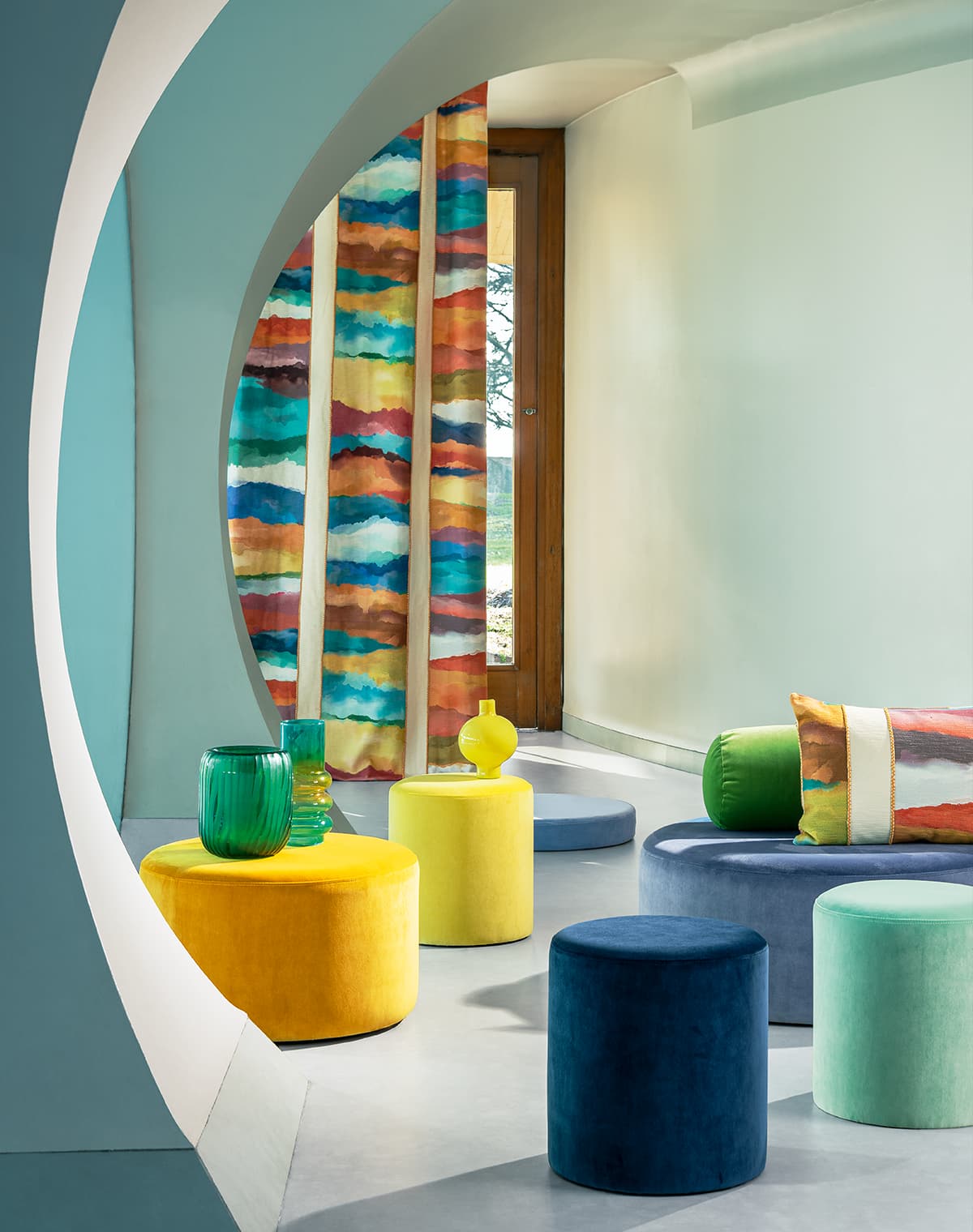 Bunte Poufs und ein Vorhang und Kissen mit dem selben Muster.